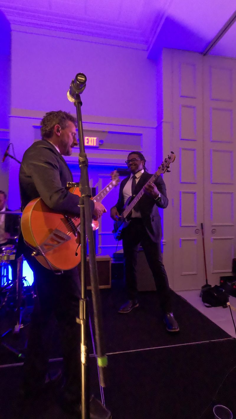 Guitar and bass side by side on stage, the drummer behind them