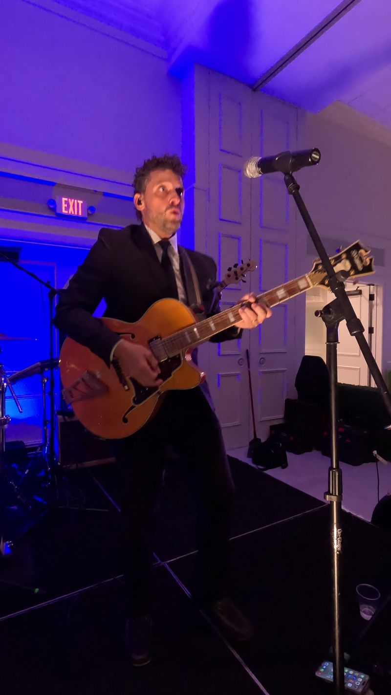 The guitarist on a hollow-body guitar at the front of the stage