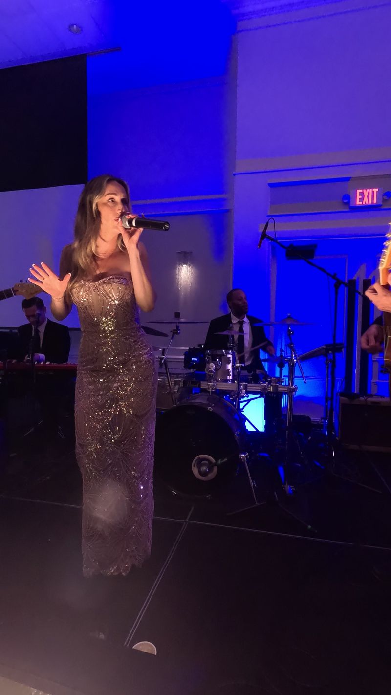The band’s singer in a sequined gown at the microphone, with keys and drums behind her