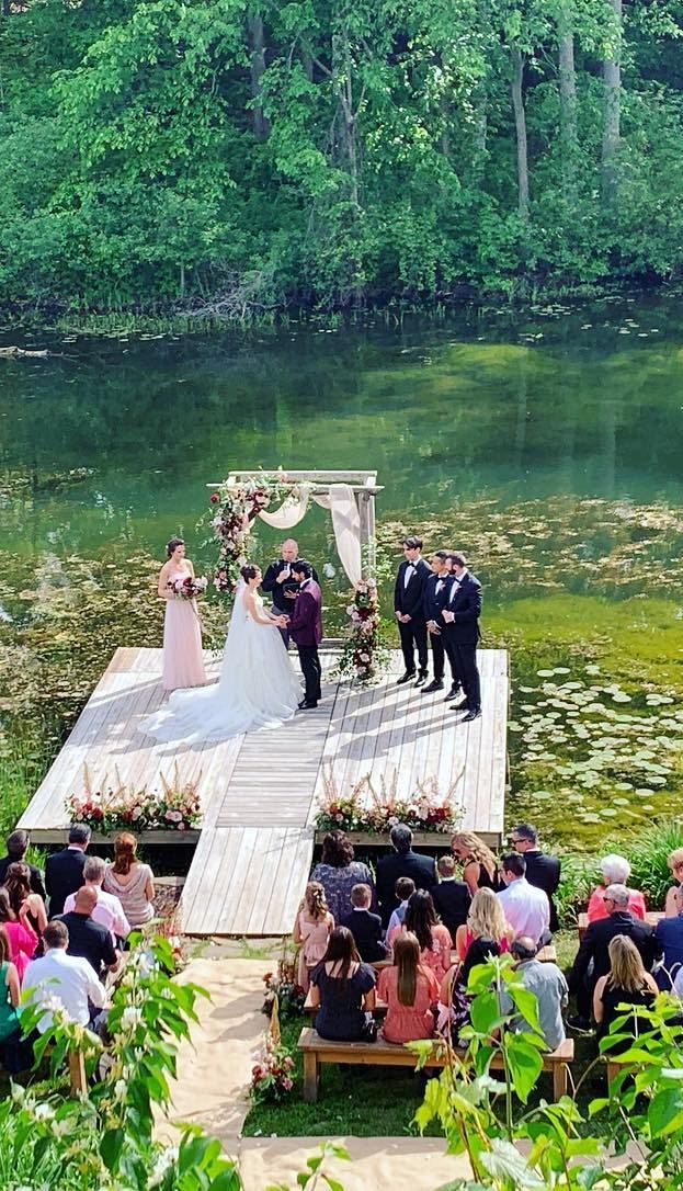 A ceremony on a wooden platform over the river, with guests seated on the bank