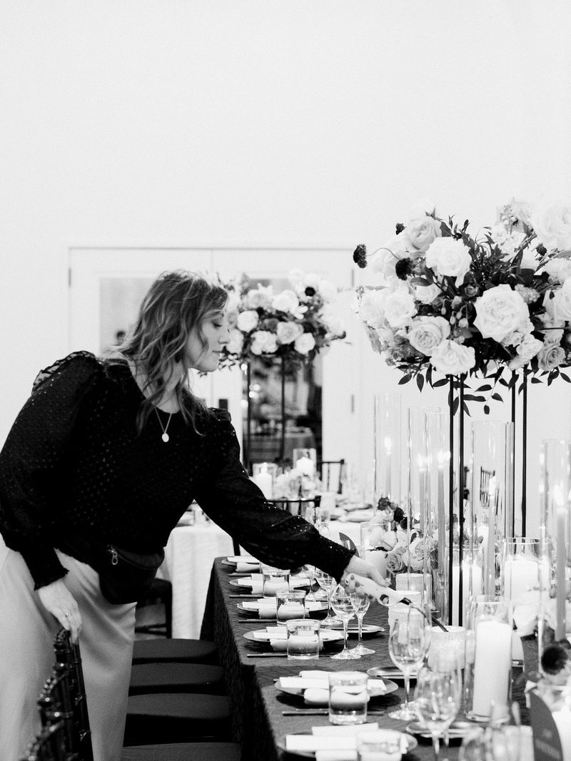 Kaeli Garcia styling a reception table set with candles and tall white florals