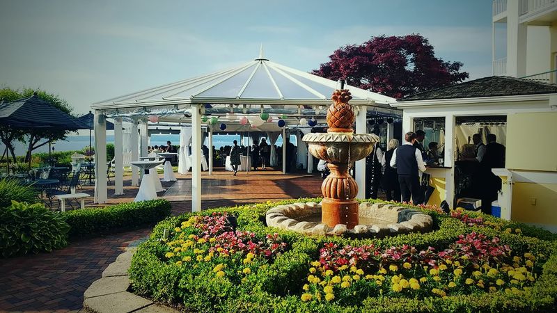 A white tent and a fountain ringed with flowers at Hotel Perry, set up for a June 2016 wedding