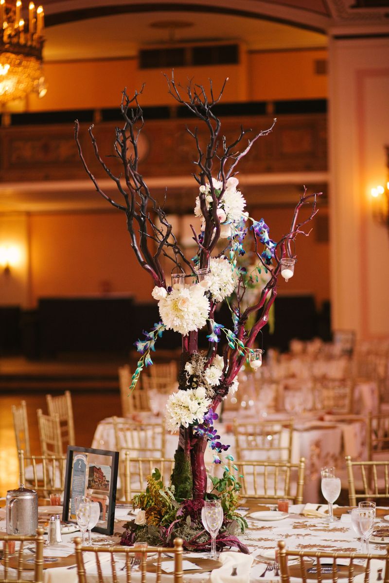 A tall branch centrepiece with white flowers in the ballroom