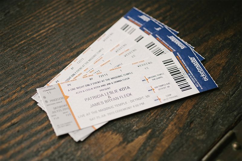 Concert-ticket wedding invitations on a wooden table