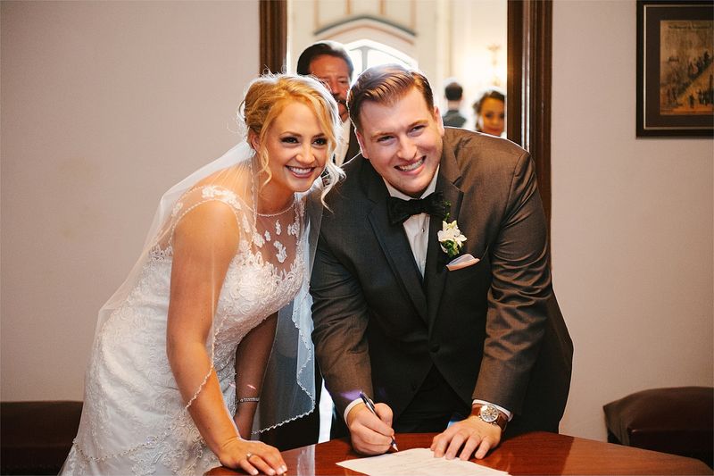 Patricia and Bryan laughing as they sign the marriage licence