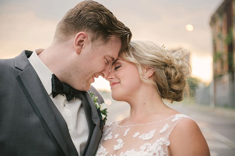 Patricia and Bryan forehead to forehead in the evening light outside The Masonic Temple