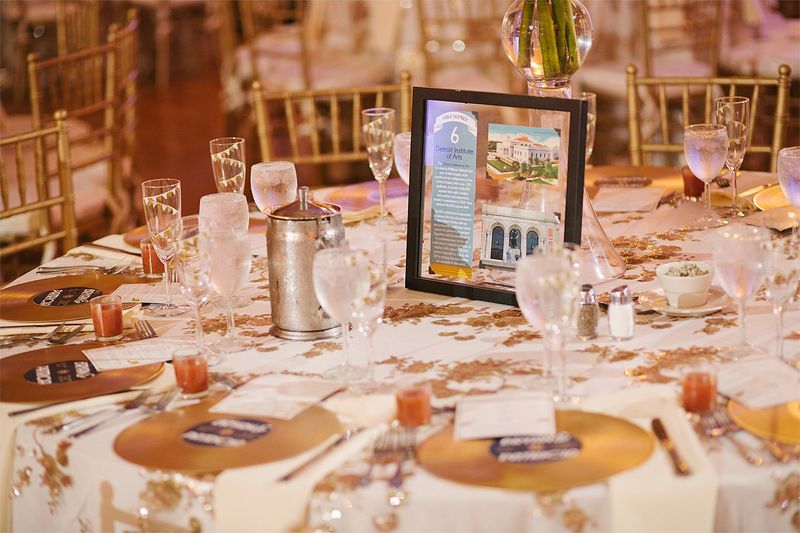 Reception tables with gold chargers and a framed table card